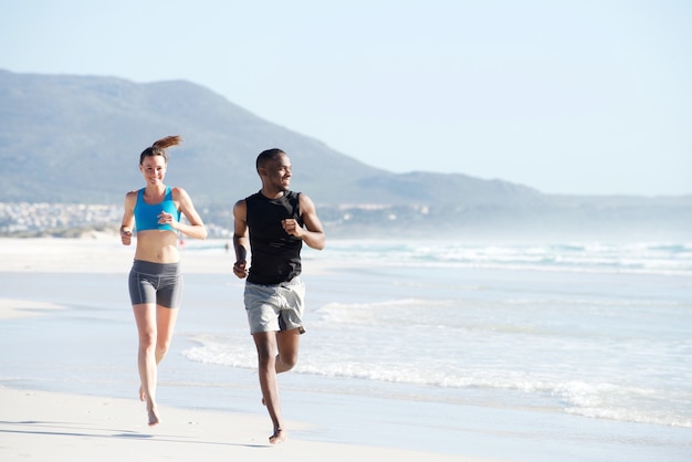 Fit giovane uomo e donna che corre lungo la spiaggia