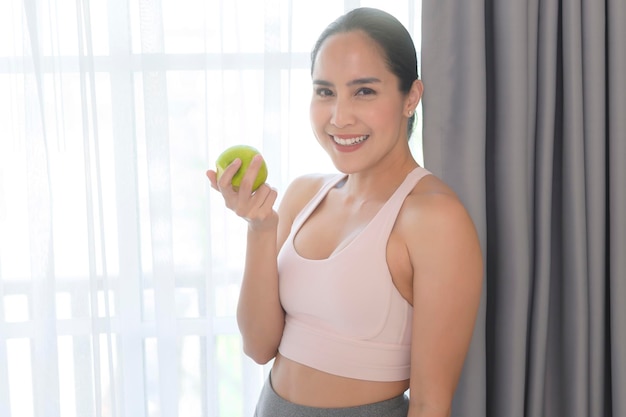 Fit young woman eating an apple after work out at home sport and healthy lifestyle concept