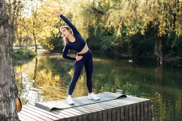 Fit young woman exercising on mat in the park