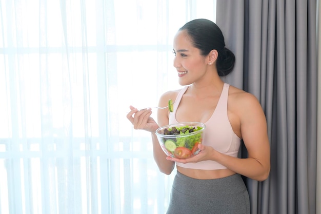 Fit young woman having salad after work out at home sport and healthy lifestyle concept