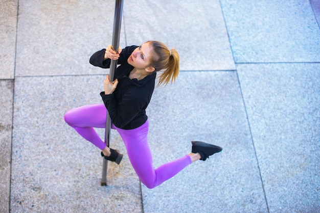 Fit young woman practicing pole dance outdoors