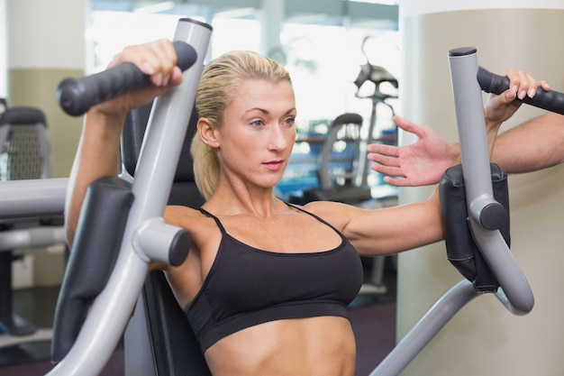 Fit young woman using fitness machine at gym