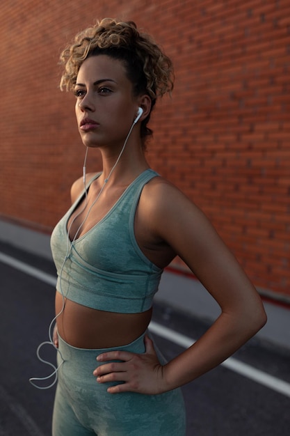 Fit young woman using her phone and earphones during a workout outdoors