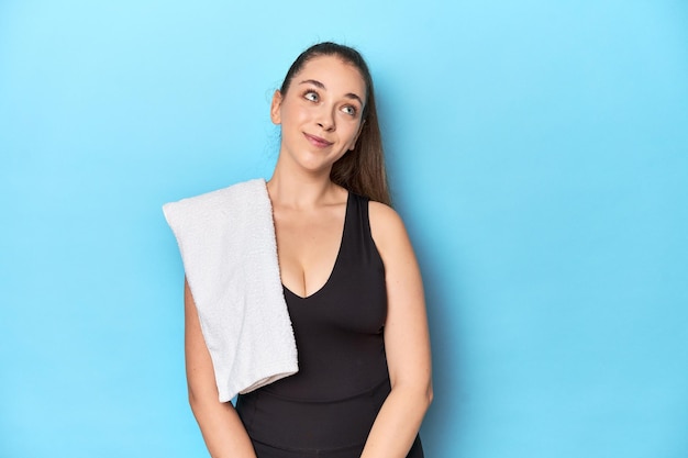 Fit young woman with a towel on her shoulder studio shot dreaming of achieving goals and purposes