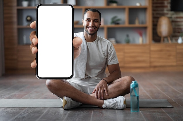 Fitness App Happy Black Man Training At Home And Showing Blank Smartphone