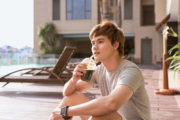 Fitness asian man drinking vegetable detox smoothie after workout.