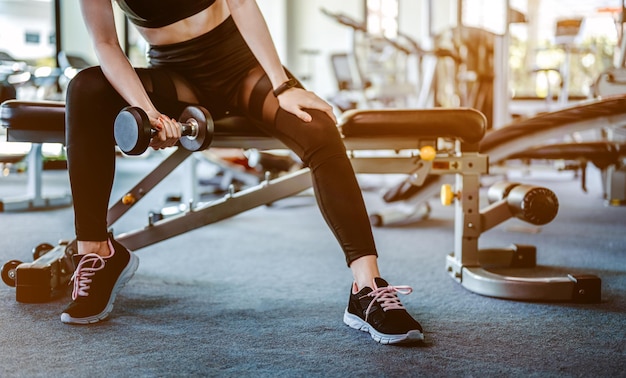 Fitness Asian Women in sportswear working out with weights over exercise bench exercising