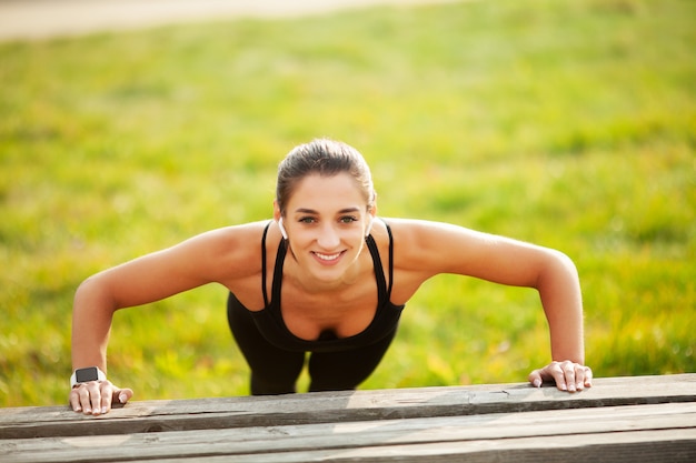 Fitness. Atletische vrouw die zich in plankpositie in openlucht bij zonsondergang bevinden. Concept van sport, recreatie en motivatie