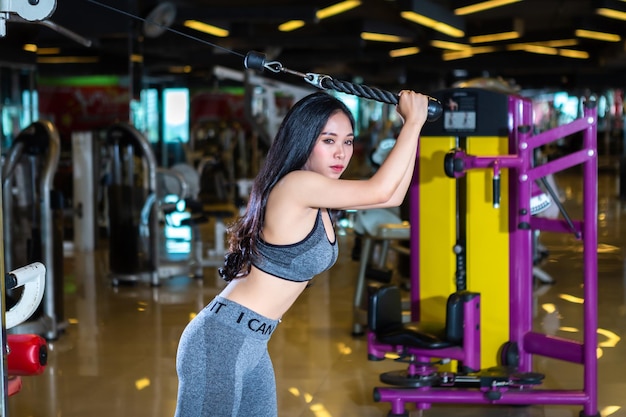 Fitness Aziatische vrouwen die oefeningen doen, trainen met roeimachine Seat Cable Rows Machine in sport gym interieur en fitness health club is openbare plaatsen met sportapparatuur Gym