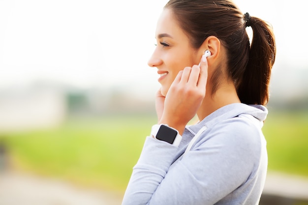 Fitness Beautiful woman drinking water and listen to music after running