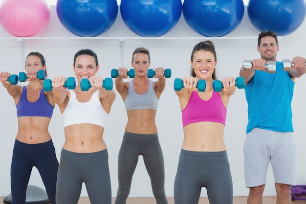 Foto lezione di fitness che si esercita con i dumbbells in ginnastica