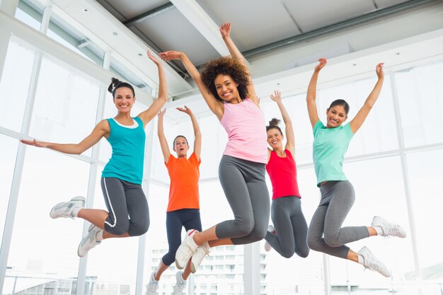 Fitness class and instructor jumping in fitness studio