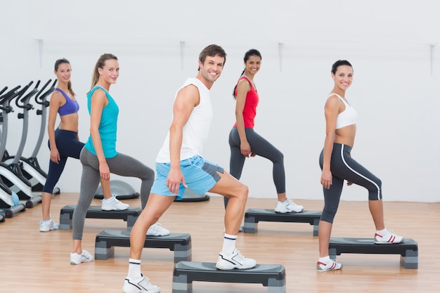 Fitness class performing step aerobics exercise