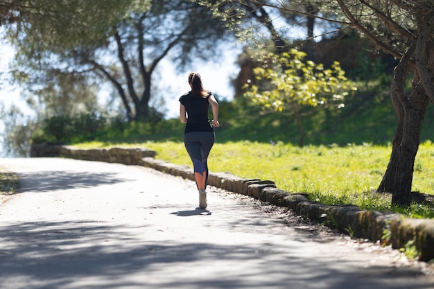 Fitness concept een volwassen vrouw in strakke leggings joggen in het groene park