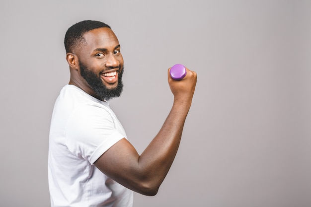 Fitness concept. Portrait of a happy african american black man with dumbbells isolated over grey background.