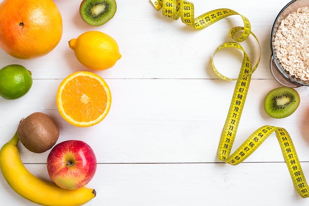 Fitness concept with fruit, bowl of oatmeal and centimeter. Top view background concept. Copy space