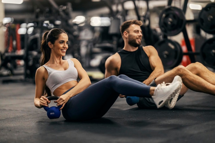 Photo fitness couple is doing kettlebell twist in a gym togehter