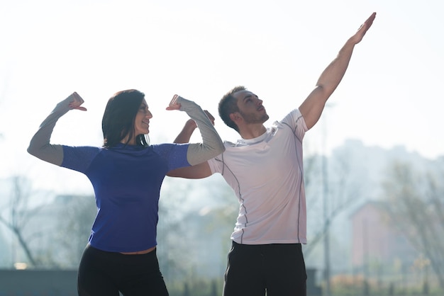 Фитнес-пара, стоящая крепко в районе городского парка и сгибающая мышцы, мускулистая спортивная модель бодибилдера, позирующая после упражнений