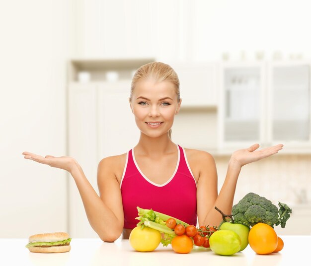 fitness, dieet en gezondheidszorg concept - lachende vrouw met fruit versus hamburger