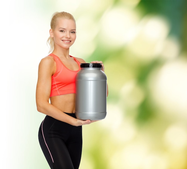 fitness and diet concept - smiling sporty woman with jar of protein