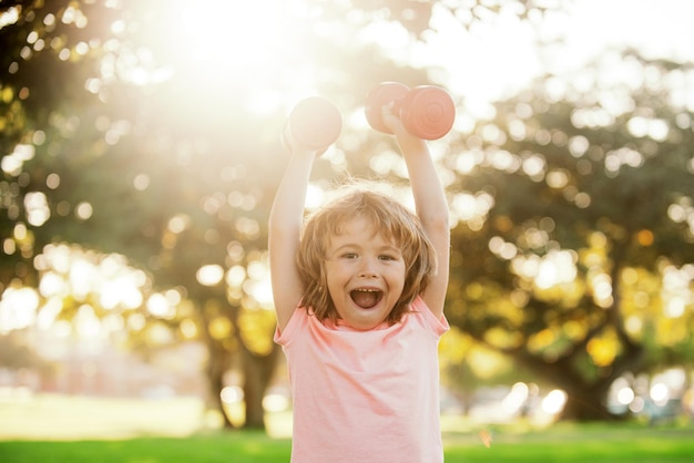 Fitness dumbbells opgewonden kind oefening workout buiten verbaasd jongen sportief kind met dumbbells in totaal