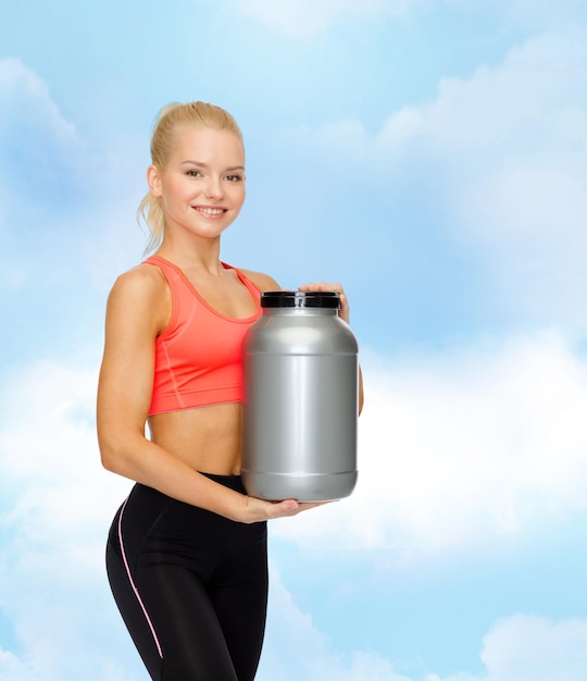 fitness- en dieetconcept - lachende sportieve vrouw met pot proteïne