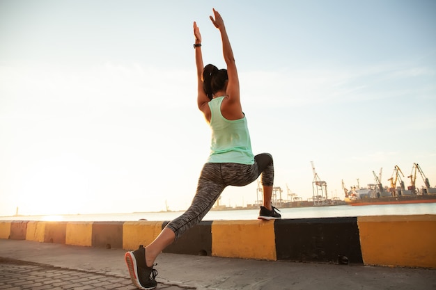 Fitness en lifestyle concept - vrouw die buiten sport doet in de buurt van de zeehaven