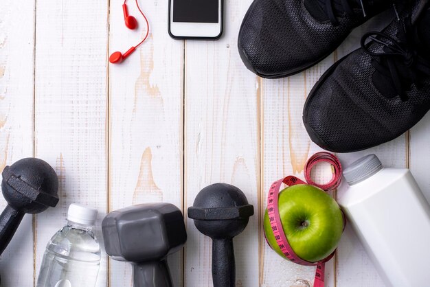 Photo fitness equipment and health food on white wooden background