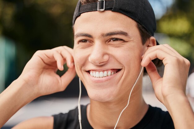 Foto esercizio di fitness e uomo che ascolta musica con gli auricolari nel parco all'aperto e natura allenamento sportivo e maschio felice con il sorriso sul viso pronto per l'allenamento con le cuffie per traccia audio e canzone