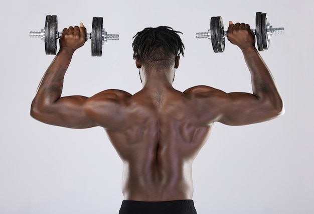 Fitness exercise and training of strong black man with dumbbell in studio Body or back of bodybuilder person doing workout to train with weights for power health and wellness or growth motivation