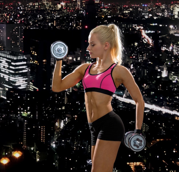 fitness, exercising and dieting concept - sporty woman with heavy steel dumbbells