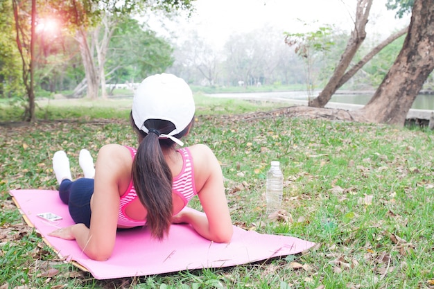 Фитнес женщина в спортивном бюстгальтере, слушать музыку смартфоном, лежа на йога коврик
