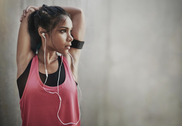 Foto fitness focus vrouw en stretching met koptelefoon op mockup ruimte voor training en training serieuze vrouwelijke atleet opwarmen op muziek voor hardloper motivatie mindset doelen en sportenergie