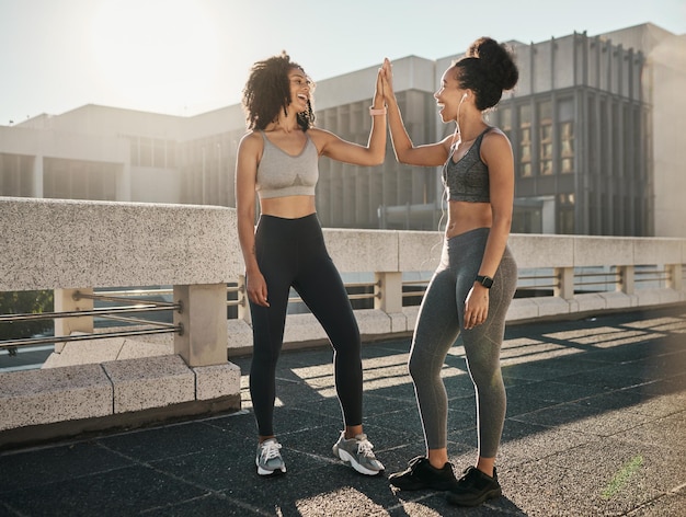 Fitness friends and high five in the city for workout exercise or healthy training together in the outdoors Happy women touching hands in partnership for sports wellness exercising or run in town