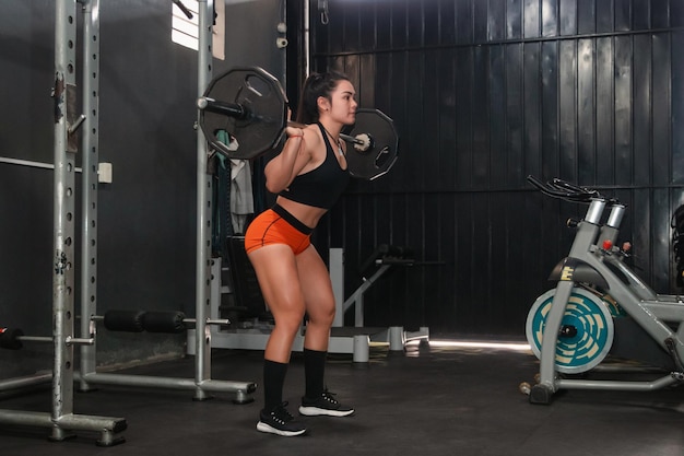 Foto ragazza fitness in procinto di eseguire uno squat con bilanciere in palestra