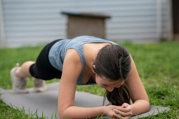 Фитнес-девушка делает акциз на лужайке во дворе своего дома