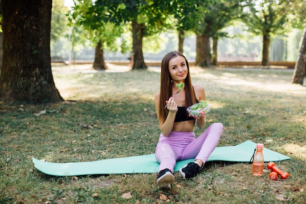 公園で健康を食べるフィットネス少女