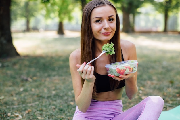 公園で健康を食べるフィットネス少女