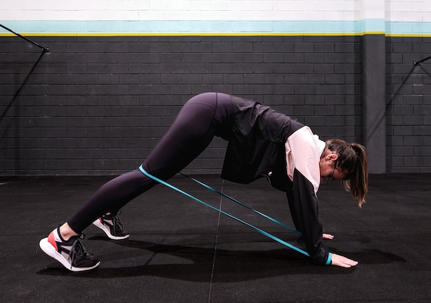 Foto ragazza di fitness che si esercita in palestra con le gomme elastiche