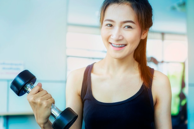 Photo fitness girl exercising with barbell in gym.