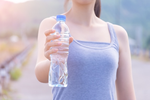 彼女の手で飲料水のボトルを保持しているフィットネス女の子