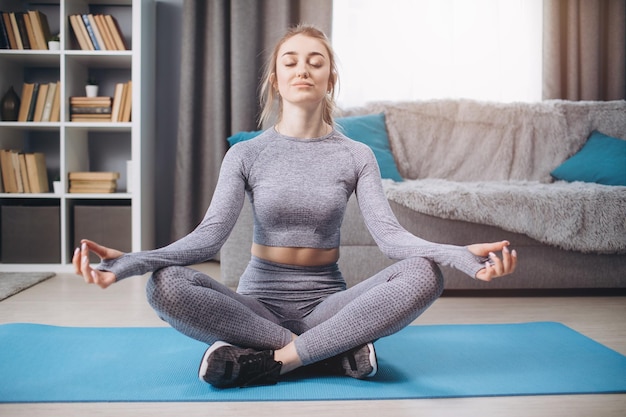 Fitness girl sitting in pose lotus at home