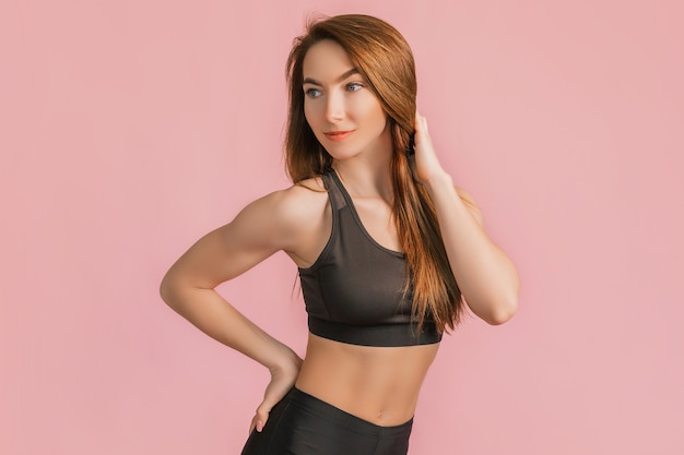 Photo fitness girl smiling in black sportswear on a pink space