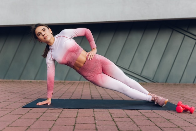 Fitness girl stands in side plank