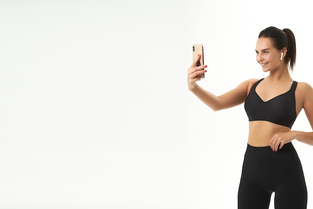 Fitness girl on training in sportswear holds a smart phone in her hands