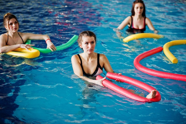 Fitness group of girls doing aerobical excercises in swimming pool at aqua park. 