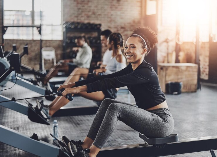 Photo fitness gym and woman on rowing machine for health wellness and body workout with class endurance exercise and female athlete on ergometer equipment for cardio training in sports center