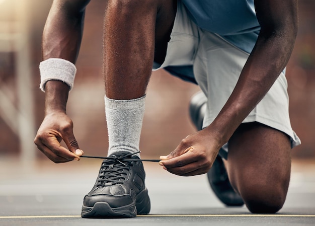 Fitness hardlopen en schoenen van zwarte man voor training voor sportmotivatie en start van training oefening gezondheid en welzijn met hardloper die zijn veters in de weg bevestigt voor cardio-energie en prestaties