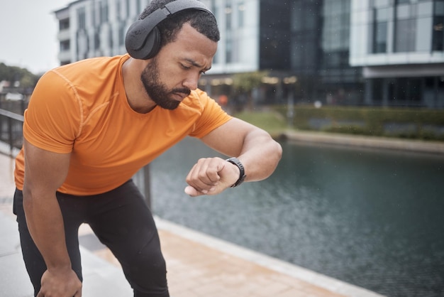 フィットネス ヘッドフォンと黒人男性と一緒にランニング トレーニングと運動時間をチェックする時計