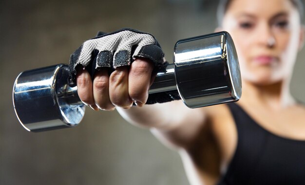 Foto concetto di fitness, assistenza sanitaria e dieta - primo piano di giovane donna sportiva con manubrio in acciaio